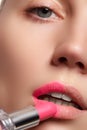 Close up portrait of attractive lips of beautiful woman. Rouging her lips with pink mate lipstick. The lady is gently smiling. Clo Royalty Free Stock Photo