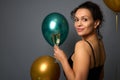 Close-up portrait of attractive mixed race woman posing with flute of champagne against gray background with beautiful golden and