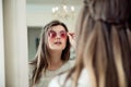 Close-up portrait of attractive modern european woman in optician store standing near mirror and trying on stylish Royalty Free Stock Photo