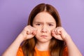 Close-up portrait of attractive offended desperate girl wiping tears crying isolated over violet purple color background