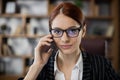 Close up portrait attractive red hair businesswoman holding cell phone talking with client Royalty Free Stock Photo