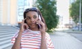 Close up portrait of attractive stylish dark skinned girl with afro hairstyle talking on mobile phone isolated on street..