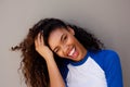 Close up attractive young black woman smiling with hand in hair against gray wall Royalty Free Stock Photo