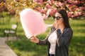 Close up portrait of attractive young girl eating cotton candy in front of pink sakura tree Royalty Free Stock Photo