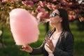 Close up portrait of attractive young girl eating cotton candy in front of pink sakura tree Royalty Free Stock Photo