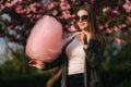 Close up portrait of attractive young girl eating cotton candy in front of pink sakura tree Royalty Free Stock Photo