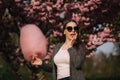 Close up portrait of attractive young girl eating cotton candy in front of pink sakura tree Royalty Free Stock Photo