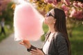 Close up portrait of attractive young girl eating cotton candy in front of pink sakura tree Royalty Free Stock Photo