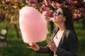 Close up portrait of attractive young girl eating cotton candy in front of pink sakura tree Royalty Free Stock Photo