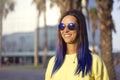 Close up portrait of an attractive young happy sports woman with blue hair and retro sunglasses outdoors in the park. Smiling Royalty Free Stock Photo