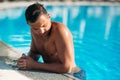 Close up portrait of attractive young man resting on edge of swimming pool Royalty Free Stock Photo