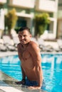 Close up portrait of attractive young man resting on edge of swimming pool Royalty Free Stock Photo