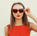 Close up portrait of attractive young woman blowing red lips sending sweet air kiss wearing a heart shaped sunglasses on white Royalty Free Stock Photo