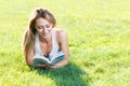 Close up portrait of an attractive young woman laying down on green grass in a park during the summer and listening to Royalty Free Stock Photo