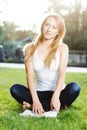 Close up portrait of an attractive young woman laying down on green grass in a park during the summer and listening to Royalty Free Stock Photo