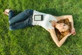 Close up portrait of an attractive young woman laying down on green grass in a park during the summer and listening to Royalty Free Stock Photo