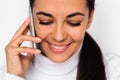 Close up portrait of attractive young woman with mobile phone looking down and face with toothy smile, on the white background. Royalty Free Stock Photo