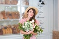 Close-up portrait of an attractive young woman in a summer dress and straw hat, holding a bouquet of flowers against a background Royalty Free Stock Photo