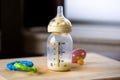 A close up portrait of a baby bottle with a bit of formula still in it standing on a wooden plank. The glass nursing bottle still Royalty Free Stock Photo