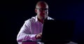 Close-up portrait of a bald man in glasses and a shirt, he sits at a laptop, emotional, nervous, thinking. Next to him