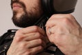 Close-up portrait of bearded biker in leather jacket fasten a motorcycle helmet. Royalty Free Stock Photo