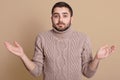Close up portrait of bearded guy spreading hands in helpless gesture, young man wearing warm knitted sweater, shrugging shoulders Royalty Free Stock Photo