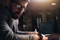 Close-up portrait of bearded man wearing eye glasses and smartwatch at night coworking loft space. Young creative manager looking