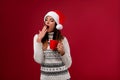 Close up portrait beautifiul caucasian woman in red Santa hat on red studio background. Christmas and New Year holiday concept