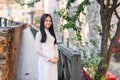 Close up portrait of beautiful asian girl dressed in Ao Dai white dress stands near the tree on wooden bridge. Royalty Free Stock Photo