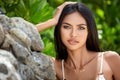 Beautiful asian girl in a white bikini posing on a beach with rocks Royalty Free Stock Photo