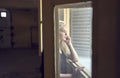 Close up portrait of beautiful blond young woman looking through hotel window Royalty Free Stock Photo