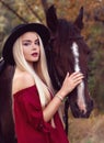 Close-up portrait of a beautiful blonde caucasian girl caressing a horse