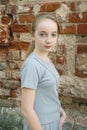 Close up portrait of a beautiful blonde girl with braids against a brick wall. Serious girl of 13-15 years old looking Royalty Free Stock Photo