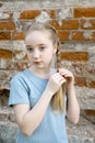 Close up portrait of a beautiful blonde girl with braids against a brick wall. Serious girl of 13-15 years old looking Royalty Free Stock Photo