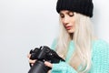 Close-up portrait of beautiful blonde girl photographer looking on DSLR camera, on white background. Royalty Free Stock Photo