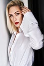 Close up portrait of beautiful blonde woman with red lips in elegant white shirt posing isolated on black background. Royalty Free Stock Photo