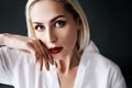 Close up portrait of beautiful blonde woman with red lips in elegant white shirt posing isolated on black studio Royalty Free Stock Photo