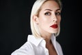 Close up portrait of beautiful blonde woman with red lips in elegant white shirt posing isolated on black studio Royalty Free Stock Photo