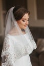 Close up portrait of beautiful bride standing by the window at home. Charming bride in white wedding dress Royalty Free Stock Photo