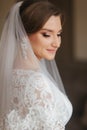 Close up portrait of beautiful bride standing by the window at home. Charming bride in white wedding dress Royalty Free Stock Photo