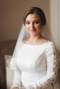 Close up portrait of beautiful bride standing by the window at home. Charming bride in white wedding dress Royalty Free Stock Photo