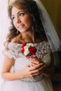 Close-up portrait of beautiful bride in wedding dress holding a cute bouquet with red and white roses dreaming her Royalty Free Stock Photo