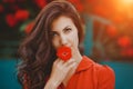 Close-up portrait of beautiful brunette woman with red rose in her lips. Toned image Royalty Free Stock Photo