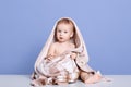 Close up portrait of beautiful covered brown and white towel, adorable cheeper posing isolated over blue background, infant kid