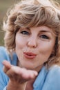 A close-up portrait of a beautiful curly girl blowing a kiss to the camera. Soft selective focus