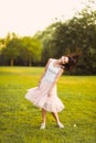 Portrait of a beautiful cute girl in a romantic brunette skirt with in a green garden posing and smiling