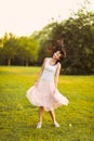 Portrait of a beautiful cute girl in a romantic brunette skirt with in a green garden posing and smiling