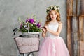 Close-up portrait of a beautiful cute little girl in a wreath of fresh flowers on her head and a basket of beautiful spring Royalty Free Stock Photo