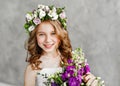 Close-up portrait of a beautiful cute little girl in a wreath of fresh flowers on her head and a basket of beautiful spring Royalty Free Stock Photo