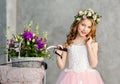 Close-up portrait of a beautiful cute little girl in a wreath of fresh flowers on her head and a basket of beautiful spring Royalty Free Stock Photo